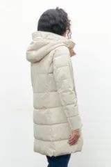 Campera capitoneada color beige, con capucha y cierre frontal con botones a presión.
