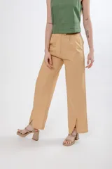 Pantalón de vestir color beige, de corte recto y tiro alto, con bolsillos laterales y aberturas en el ruedo.