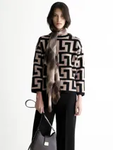 Sweater de punto con cuello redondo y mangas 3/4. Diseño con motivos geométricos en color visón y negro. Incluye una bufanda fina con estampado a cuadros en tonos marrones.