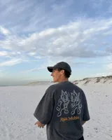 Remera marrón oversize de manga corta con estampado gráfico en la espalda de dos gatos de estilo retro con cuchillos y texto "Kahoa Industries".