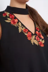 Vestido negro sin mangas con bordado de flores en hilo de seda color coral y dorado en el escote.