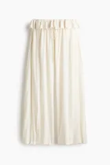 Pantalón oversized de tiro bajo color blanco crudo, confeccionado en viscosa con alforzas, ribetes de encaje, cordón de ajuste y ribete de volado en la cintura.