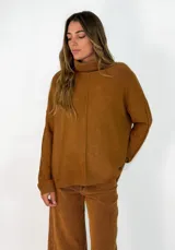 Sweater de punto color tostado, con cuello alto, diseño holgado y costura central vertical visible.