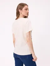 Remera de corte holgado color crema con estampado gráfico frontal estilo retro que representa un paisaje con una camioneta y la leyenda Rusty Hills.