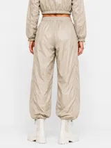 Pantalon estilo parachute verde militar con cintura elastizada ajustable mediante cordón, bolsillos laterales y puños ajustables en los tobillos.