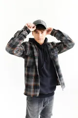 Sobrecamisa de paño escocesa con estampado a cuadros en tonos negro, gris y naranja. Tiene cuello camisero, cierre frontal con botones, dos bolsillos con solapa en el pecho y puños abotonados.