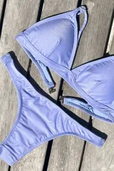 Bikini de dos piezas color marrón, con corpiño triangular fijo con corte bajo el busto, breteles regulables con hebilla y almohadillas desmontables. La bombacha es vedetina con frunce elástico en los costados.