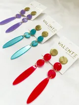 Aros colgantes con base dorada y dijes de acrílico violeta y blanco.