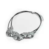 Collar plateado con tres dijes irregulares y cordón doble de cuero sintético negro.