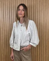 Camisa de cuello redondo y manga larga abullonada, con diseño a rayas en tonos rosado y blanco.