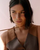 Gargantilla tipo choker de tiento de gamuza marrón con dije de flor en acrílico espejado dorado.
