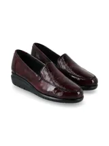 Zapato mocasín slip-on de cuero charol color bordó, con suela anatómica negra en contraste y diseño atemporal.
