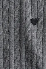 Buzo de punto trenzado con cuello redondo, manga larga y detalle de corazón bordado en el pecho. Presenta terminaciones acanaladas en cuello, puños y ruedo.