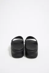 Chancla de plataforma con diseño de líneas orgánicas y suela con acabado dentado. Presenta una banda superior ancha con el logo grabado en relieve.