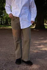 Jean de corte recto confeccionado en denim lavado color marrón, con aplique de parche en contraste en una de las piernas que presenta un diseño de flor bordada.