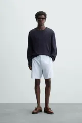 Bermuda azul marino de corte regular fit, confeccionada en tejido de algodón y lino. Cuenta con bolsillos frontales y traseros, cierre frontal con cremallera y botón.