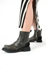 Botas de cuero negro con elásticos laterales, detalle de gamuza en el talón y suela de goma con plataforma.