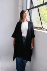 Poncho abierto de tejido de punto color negro, con mangas tres cuartos y bolsillos laterales.