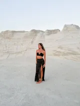 Top de hilo negro con tirantes finos cruzados en el frente y abertura circular en el centro.