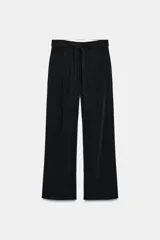 Pantalón negro de tiro medio con pierna ancha y pliegues frontales. Incluye un cinturón de lazo en el mismo tejido para ajustar a la cintura.