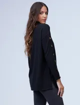 Polera negra de tejido soft con cuello alto y mangas largas con aplique de botones.