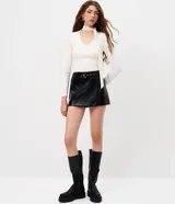 Blusa entallada de microfibra color blanco, con escote en V, mangas largas y detalle de frunces en los laterales. Presenta un lazo integrado en el cuello que permite anudarlo, aportando un toque sofisticado al diseño.