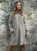 Tapado largo de paño de lana con estampado de espiga en tonos beige y marrón. Cuenta con cierre frontal de cremallera, cuello alto y bolsillos laterales.