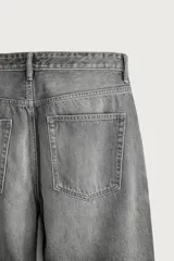 Jeans de denim de algodón en color azul con efecto desgastado, tiro medio y corte recto de ajuste holgado (loose fit). Cuenta con diseño clásico de cinco bolsillos y cierre frontal con cremallera y botón.