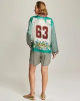 Camisa de viscosa con diseño estampado que combina motivos florales en el frente y patrón de cuadros en mangas y espalda. Presenta cuello clásico, cierre frontal con botones y mangas largas con puños definidos.