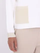 Sweater blanco de tejido de punto con cuello redondo y mangas largas. Tiene dos bolsillos cuadrados de lurex color beige en el frente.