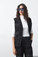 Chaleco de estilo utilitario color bordó con pespuntes blancos a contratono. Presenta solapas, cierre frontal con botones, bolsillos delanteros y un diseño estructurado.