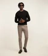 Pantalón masculino corte slim confeccionado en sarga de algodón con elastano. Presenta cierre de botón y cremallera, bolsillos laterales y traseros, y diseño liso sin estampados.