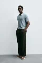 Polo de manga corta, color celeste pálido, con cuello solapa y abertura frontal en V. Tejido de punto con textura acanalada vertical.