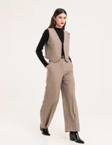 Chaleco de vestir gris oscuro con textura tipo tweed, escote en V y botones frontales. Corte levemente entallado y largo a la cintura.