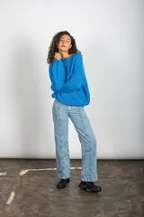 Jean de tiro alto confeccionado en denim de algodón, con diseño de piernas amplias y rectas, cuatro bolsillos, cierre de botón y detalles de ribetes al frente.
