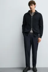 Pantalón regular fit color azul marino, confeccionado en tejido elástico. Cuenta con bolsillos frontales, bolsillos traseros de vivo con botón y cierre frontal con cremallera y botón.