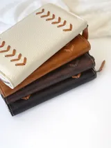 Billetera grande de cuero color marrón con cierre metálico y detalle de costuras en forma de espiga. Incluye monedero interno y espacio para billetes extendidos.