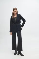 Blazer de denim azul con solapas y puños decorados con volados desflecados. Presenta un corte estructurado con bolsillos laterales y cierre frontal.