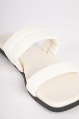 Sandalias bajas negras de símil cuero con dos tiras acolchonadas.