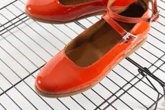 Chatas rojas de cuero charol, con pulsera al tobillo con hebilla y suela color caramelo.