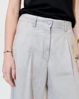 Pantalón de lino celeste con efecto vintage, corte ancho, tiro medio, pinzas delanteras, bolsillos laterales inclinados, raya de aplomo y bolsillos traseros ojal y con tapa.