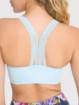 Top deportivo de soporte medio en color celeste, con diseño de espalda con tirante central grueso y detalles de encaje en la banda inferior y los tirantes. Incluye almohadillas removibles.