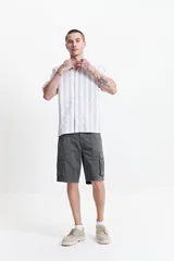 Camisa de manga corta a rayas verticales blancas y grises, con cuello camisero y corte recto. El modelo usa talle M.