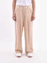 Pantalón de vestir color beige, de corte ancho y tiro alto, con pinzas en la cintura y textura arrugada.