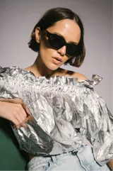 Blusa plateada con escote off-shoulder y mangas 3/4 abullonadas con elástico en los puños.