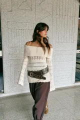 Jersey de punto color crema, con escote Bardot (hombros descubiertos) y manga larga acampanada. Presenta tejido calado con patrones horizontales y bajo festoneado.