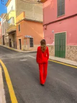 Pantalón rojo de corte recto y tiro alto, con bordado tipo broderie en la parte inferior de las piernas.