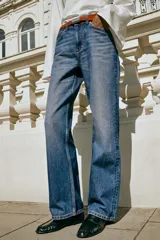 Jeans de tiro alto y corte recto de pernera larga, con diseño clásico de cinco bolsillos y costuras en contraste. Cierre frontal con cremallera y botón metálico.