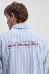 Camisa de manga larga con diseño a rayas verticales en color verde y blanco, cuello clásico y estampa con bordado en la espalda con la frase "Expect Nothing, appreciate everything".