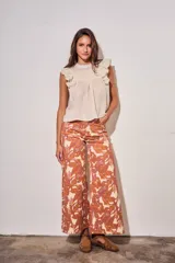 Blusa sin mangas de color crudo, con diseño oversize, cuello redondo y detalles de nido de abeja bordado en el pecho, acompañado de volados en los hombros.
